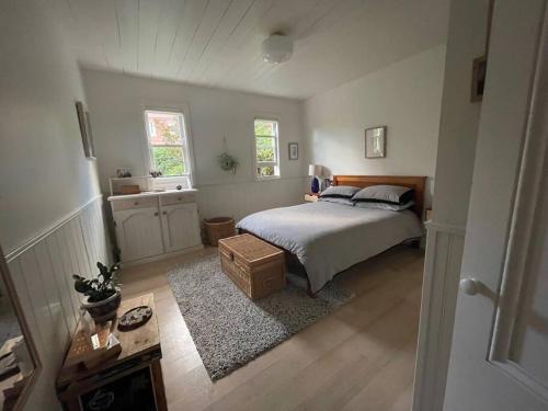 Writer's Cottage, luxurious oasis in the heart of North Hobart في هوبارت: غرفة نوم بسرير وطاولة ونوافذ