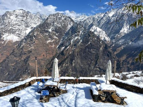 two chairs and umbrellas in the snow on a mountain at Faraway Cottages, Auli in Joshīmath