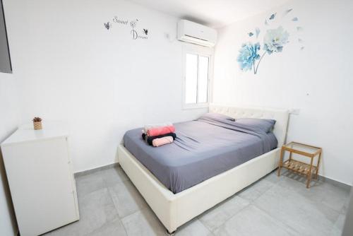 a bed in a white room with a window at Beautiful apartment near Tel Aviv in Bat Yam