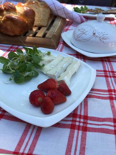 a plate of cheese and strawberries on a table at Tornácos Tanya Vendégház*** és Gasztroporta in Kiskunmajsa