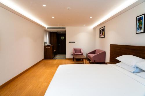 a hotel room with a bed and two chairs at Lilac Hotel Guruvayur in Guruvāyūr