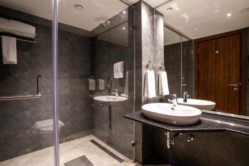 a bathroom with two sinks and a glass shower at Lilac Hotel Guruvayur in Guruvāyūr