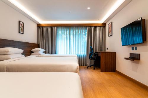 a hotel room with two beds and a desk at Lilac Hotel Guruvayur in Guruvāyūr