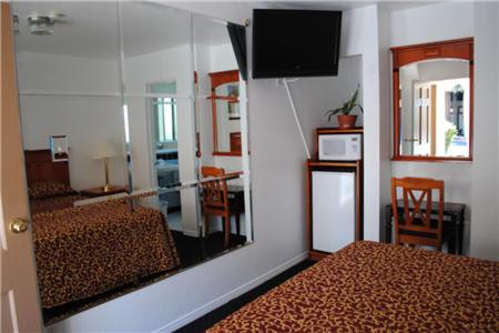 a bedroom with a mirror and a bed and a television at Rose Bowl Motel in Los Angeles
