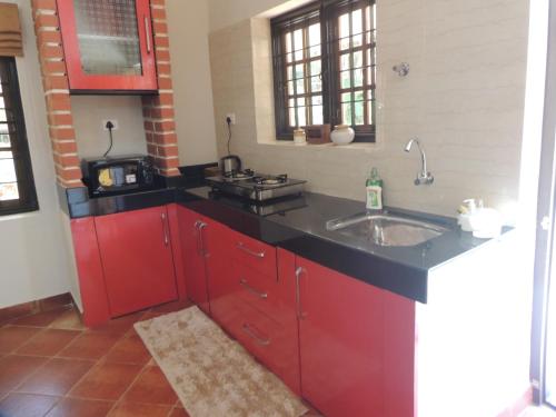 una cocina con armarios rojos y fregadero en Shimmering View en Kalyānpur