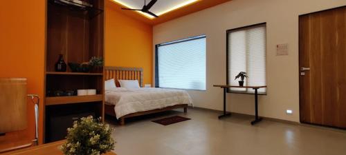 a bedroom with a bed and a table and a window at SUPRITI'S FARMINGTON SPLASH RESORT in Karjat