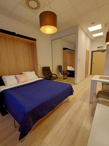 Schlafzimmer mit einem Bett mit blauer Decke in der Unterkunft Zlatarooms 310 in Warschau