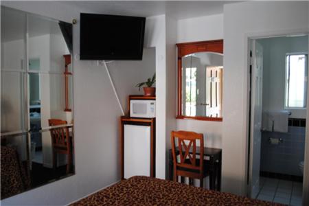 a bedroom with a bed and a television on a wall at Rose Bowl Motel in Los Angeles