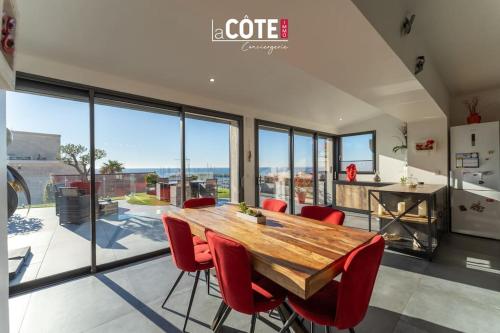 une cuisine et une salle à manger avec une table en bois et des chaises rouges dans l'établissement Terrasse vue mer - 8 Couchages, à Sausset-les-Pins