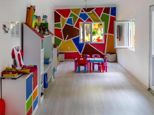 a room with a table and chairs and a colorful wall at Asteria Collection Side in Side