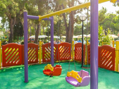 a playground with two swings and a slide at Asteria Collection Side in Side