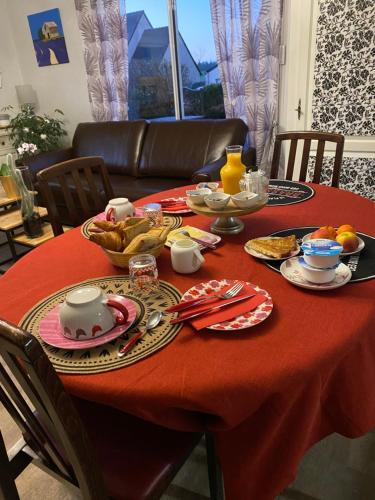 una mesa con un mantel rojo con comida. en Chambre d'Hôtes La Marie Pierre, en Pluherlin