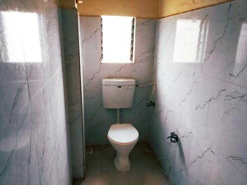 Shri Krupa Homestay في دايف إيغار: حمام صغير مع مرحاض ونافذتين