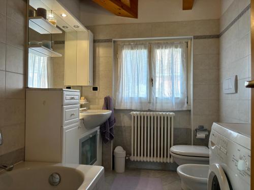 łazienka z umywalką, toaletą i oknem w obiekcie Apartment with balcony and garage Dongo - Larihome A48 w mieście Dongo