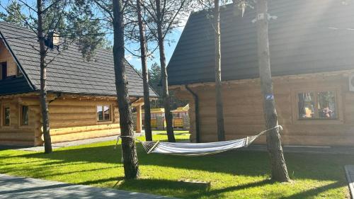 a hammock hanging from two trees in front of a house at Ośrodek u Polaka-domek góralski in Radkowice