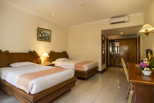 a hotel room with two beds and a desk at Parigata Resorts and Spa in Sanur