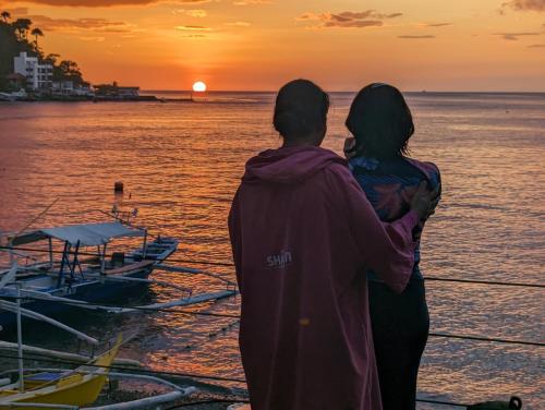 a man and woman standing on a dock looking at the sunset at Aquaventure Reef Club in Mabini