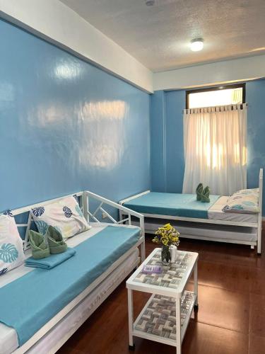 ein Wohnzimmer mit 2 Betten und einem Tisch in der Unterkunft Sassy's Place II in Baguio City