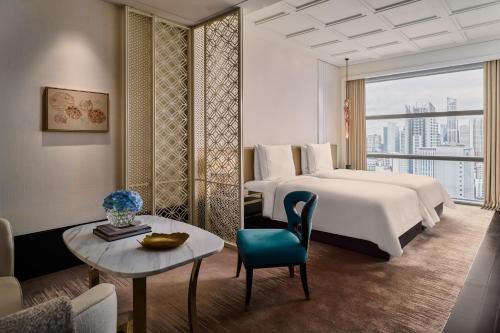 a hotel room with a bed and a table and a couch at Rosewood Bangkok in Bangkok