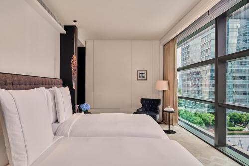a bedroom with a white bed and a large window at Rosewood Bangkok in Bangkok
