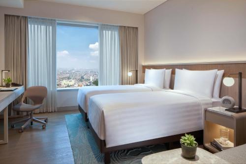 a hotel room with a bed and a desk and a window at PARKROYAL Serviced Suites Jakarta in Jakarta