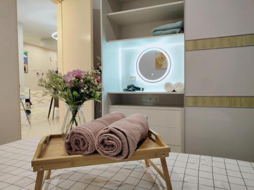 un baño con toallas en un banco con un jarrón de flores en ZuncyT11, Medini,Legoland, Gelang Patah, Johor Bahru, en Nusajaya