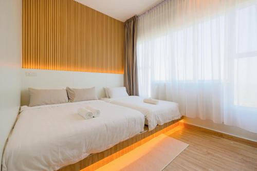 a bedroom with two beds and a large window at MujiZen Retreat Seaview Apartment Amber Cove in Melaka