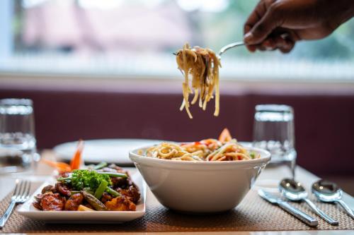 a person is eating noodles from a bowl of food at Lilac Hotel Guruvayur in Guruvāyūr