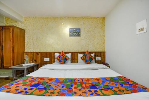 a bedroom with a large bed with a colorful comforter at FabHotel Monalisa in Manāli