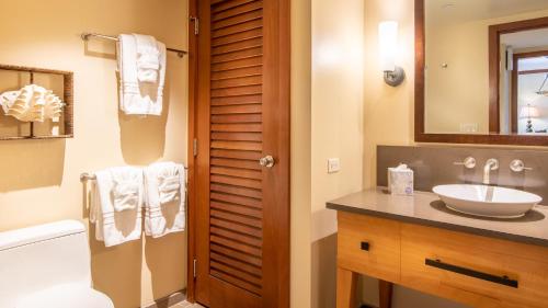 a bathroom with a sink and a toilet and a mirror at Ko Olina Beach Villas B602 in Kapolei