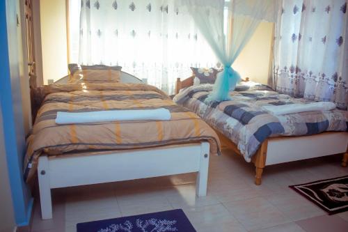 two twin beds in a room with a window at Balozi Luxury Homes in Nanyuki