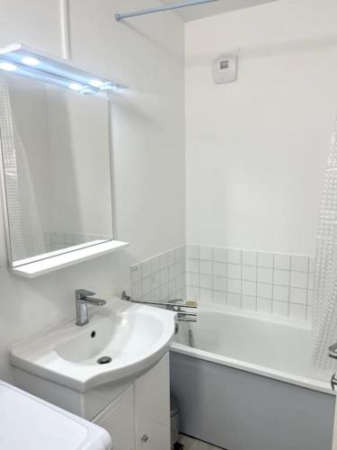 une salle de bain blanche avec un lavabo et un miroir dans l'établissement VULCAIN 2, 11ème, Ile de Nantes, 4pers, parking inclus, à Nantes