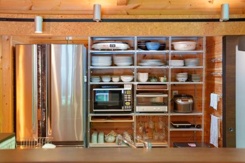 a kitchen with a refrigerator and some dishes on shelves at Logcabin Miyagawa in Nasu -那須 宮川邸- in Nasu