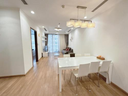 - une salle à manger et un salon avec une table et des chaises blanches dans l'établissement Vinhomes Times City 3BR, à Hanoï