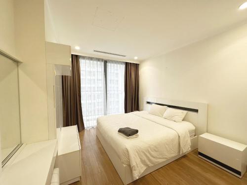 - une chambre avec un lit blanc et une fenêtre dans l'établissement Vinhomes Times City 3BR, à Hanoï