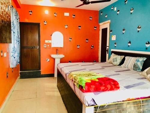 ein Schlafzimmer mit einem Bett mit einer orangefarbenen Wand in der Unterkunft Shree Hotels in Bhagalpur