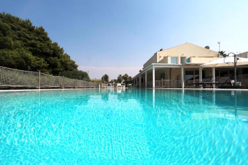 a large pool of blue water in front of a house at Salicornia - Sea view villa with pool in Marsala