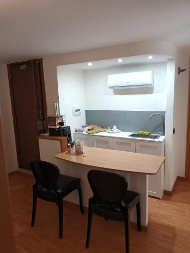 a kitchen with a wooden table and two black chairs at B&B 30 mt dal Duomo in Benevento