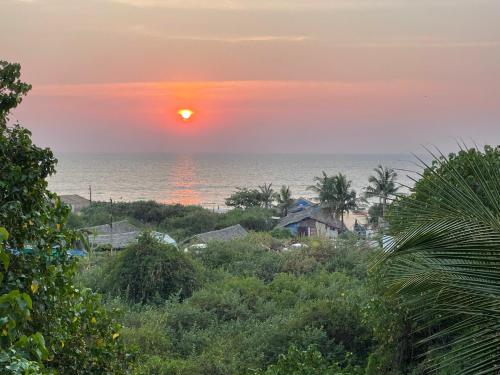 una puesta de sol sobre el océano con casas y árboles en Beach front villa en Calangute