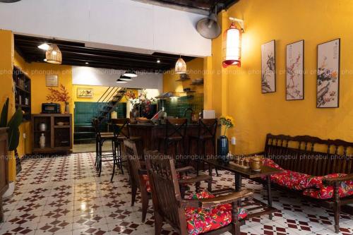 a restaurant with yellow walls and tables and chairs at Ben Thanh Vietnamese cultural house by SSens Homes in Ho Chi Minh City