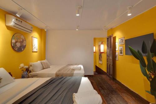 a bedroom with two beds and yellow walls at Ben Thanh Vietnamese cultural house by SSens Homes in Ho Chi Minh City