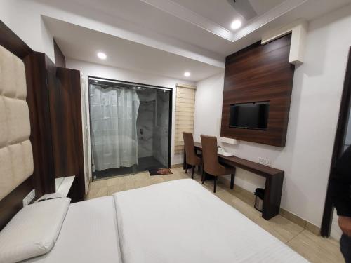 a bedroom with a bed and a desk and a tv at HOTEL AROMA in Kurukshetra