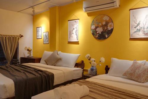 Duas camas num quarto com paredes amarelas em Ben Thanh Vietnamese cultural house by SSens Homes em Ho Chi Minh
