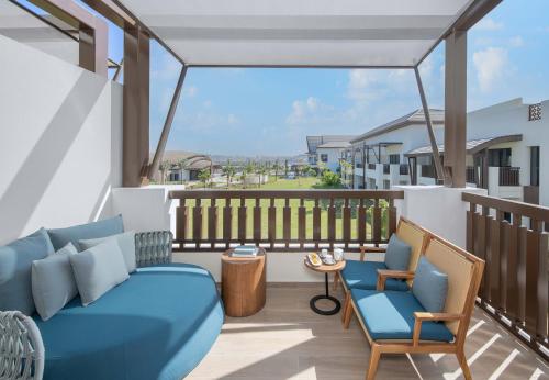 a balcony with a blue couch and two chairs at Anantara Mina Ras Al Khaimah Resort in Ras al Khaimah