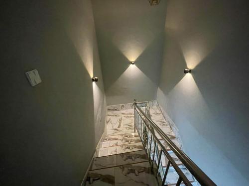 Un escalier avec deux lumières sur le mur et un sol en marbre dans l'établissement YE BISA FIE HOTEL, 