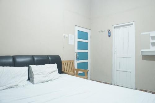 a bedroom with a white bed and a door at OYO 93654 Gr Kost Kaladan in Rantau