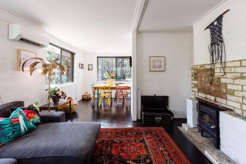 a living room with a couch and a fireplace at Bushy Sleeps - Eco Friendly Tranquil Escape in Gnarabup
