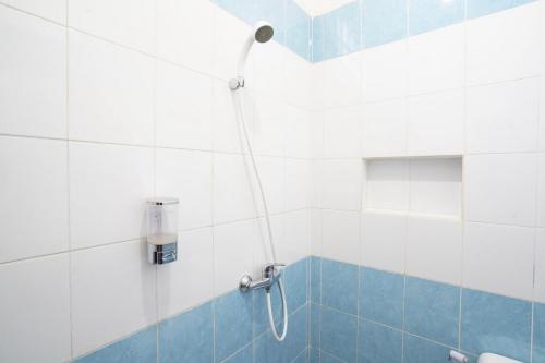 a bathroom with a shower with blue and white tiles at Hotel O Gr Kost Kaladan in Rantau
