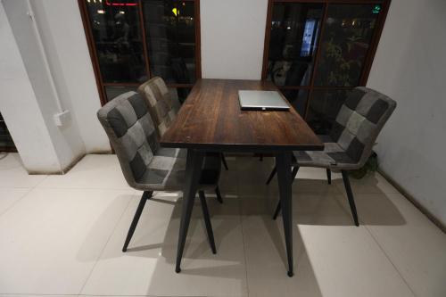 a wooden table with two chairs and a laptop on it at OYO 93667 Penginapan Pelangi in Batam Center