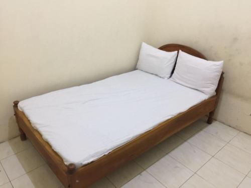 a bed with white sheets and pillows in a room at SPOT ON 93670 Homestay Vicky 2 Syariah in Sidoarjo